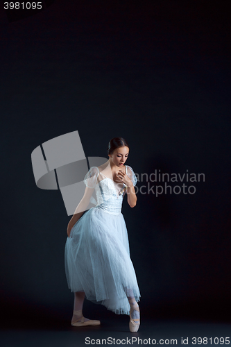 Image of Portrait of the classical ballerina in white dress on black background