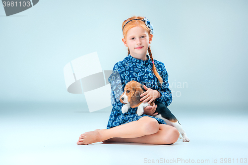 Image of The happy girl and a beagle puppie on gray background