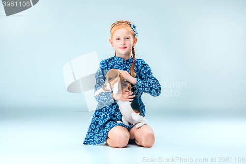 Image of The happy girl and a beagle puppie on gray background