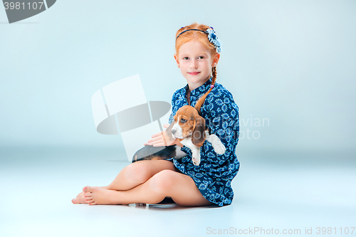 Image of The happy girl and a beagle puppie on gray background