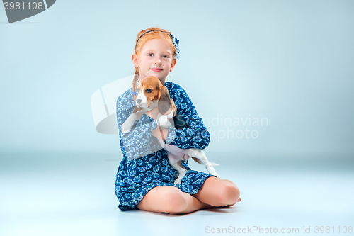 Image of The happy girl and a beagle puppie on gray background