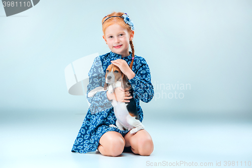 Image of The happy girl and a beagle puppie on gray background