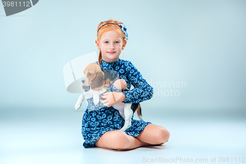 Image of The happy girl and a beagle puppie on gray background