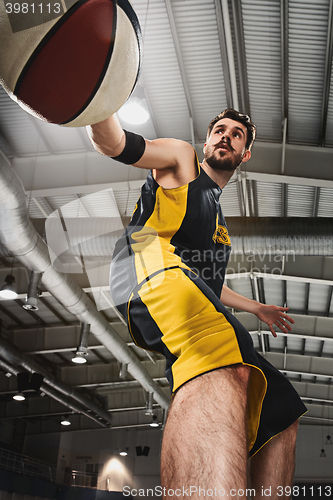 Image of The portrait of a basketball player with ball against gray gym background