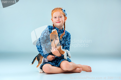 Image of The happy girl and a beagle puppie on gray background