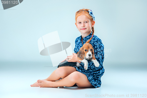 Image of The happy girl and a beagle puppie on gray background