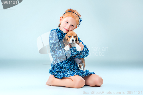 Image of The happy girl and a beagle puppie on gray background