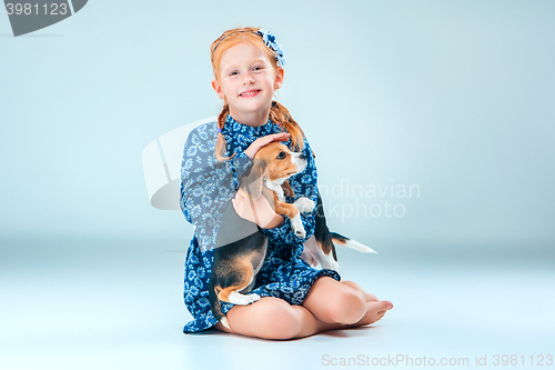 Image of The happy girl and a beagle puppie on gray background