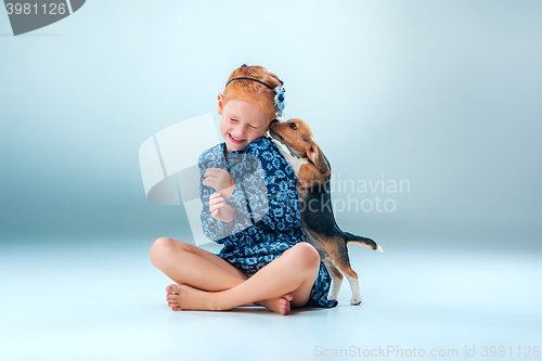 Image of The happy girl and a beagle puppie on gray background