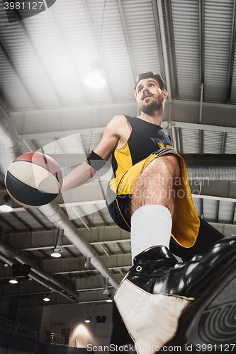 Image of The portrait of a basketball player with ball against gray gym background