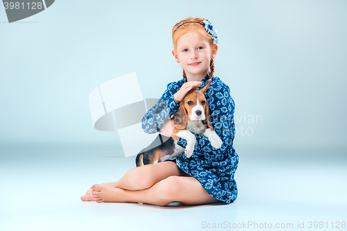 Image of The happy girl and a beagle puppie on gray background