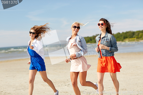 Image of group of smiling women in sunglasses on beach