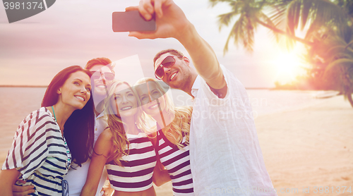 Image of happy friends taking selfie by smartphone on beach