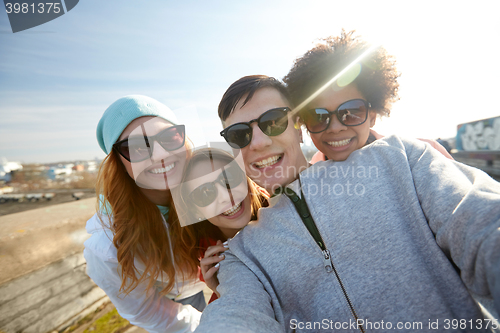 Image of group of happy friends taking selfie on street