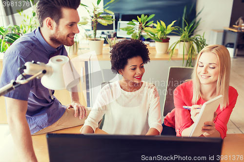 Image of happy creative team with computer in office