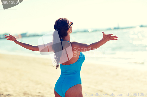 Image of young woman in swimsuit posing on beach