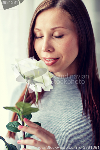 Image of happy woman smelling big white rose at home