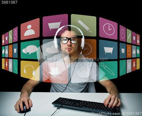 Image of man in headset with computer and icons on screen