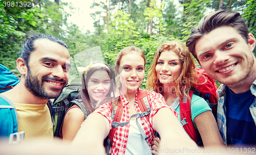 Image of friends with backpack taking selfie in wood