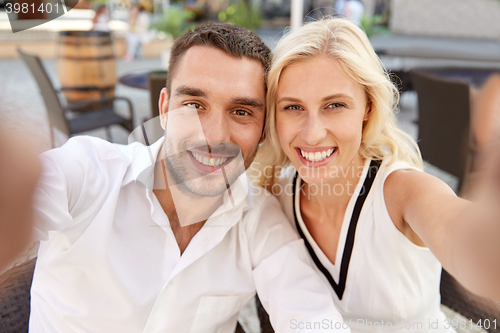 Image of happy couple taking selfie at restaurant terrace