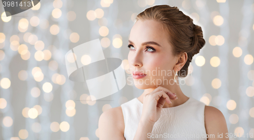 Image of smiling woman in white dress with diamond jewelry