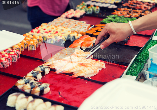 Image of close up of hand with tongs taking sushi