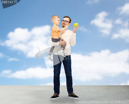 Image of happy father and little son with green apple