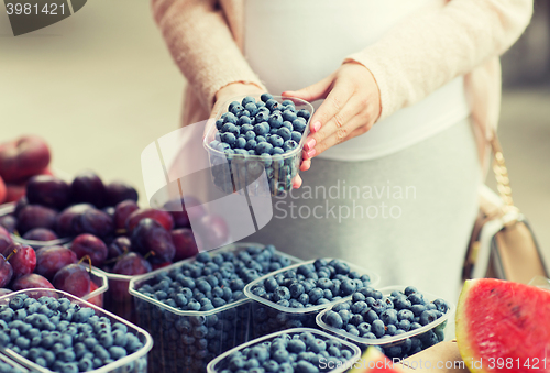 Image of pregnant woman buying blueberries at street market