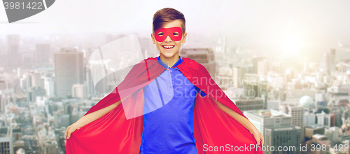 Image of boy in red superhero cape and mask over city