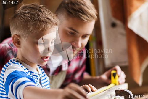 Image of father and son with ruler measure wood at workshop