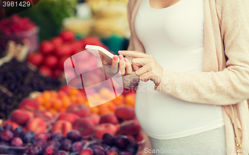 Image of pregnant woman with smartphone at street market