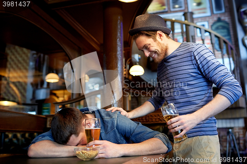 Image of male friends drinking beer at bar or pub