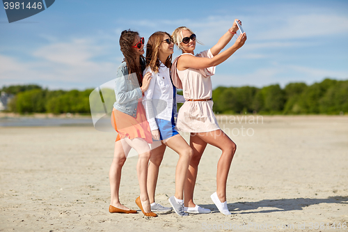 Image of group of smiling women taking selfie on beach