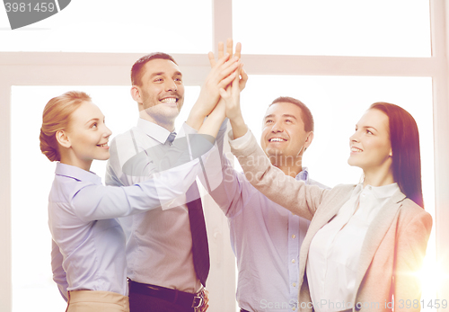 Image of happy business team giving high five in office