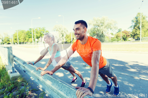 Image of close up of happy couple doing push-ups outdoors
