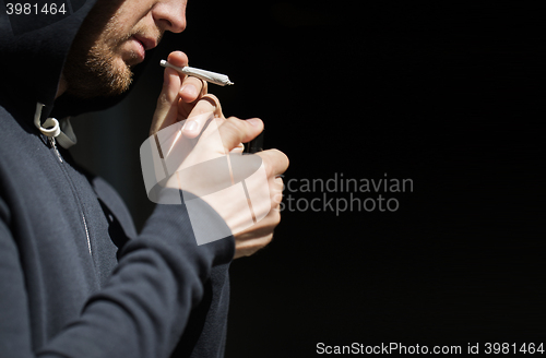 Image of close up of addict lighting up marijuana joint