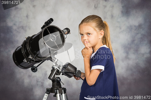 Image of Seven-year girl looks at the sky while standing at the telescope