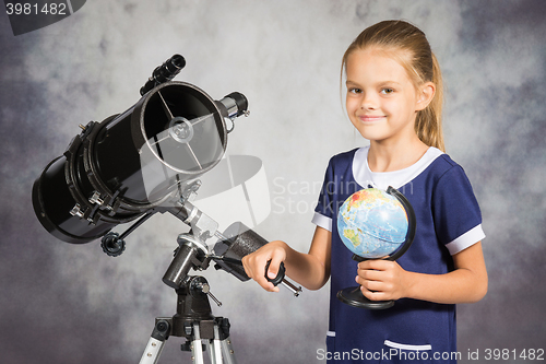 Image of Seven-year girl is happy with the globe in a reflector telescope