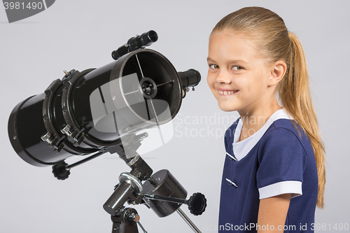 Image of The young astronomer at the telescope is smiling and looking to the frame