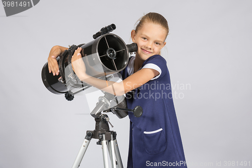 Image of Seven-year girl hugging her given reflector telescope