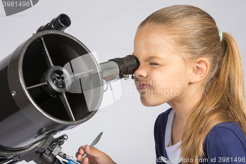 Image of The young astronomer looks through the eyepiece of the telescope and record results