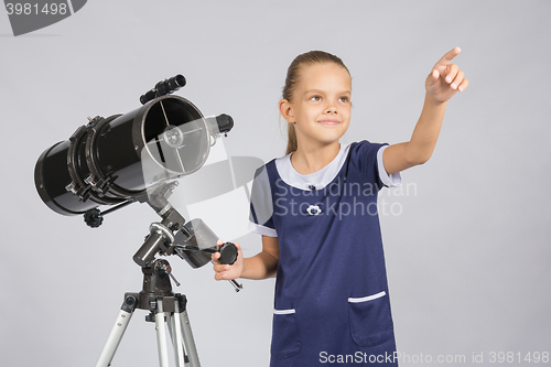 Image of The young astronomer shows the starry sky while standing at the telescope