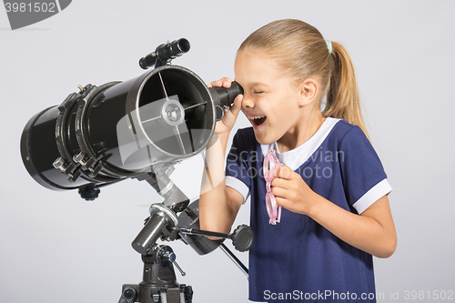 Image of Seven-year girl with interest and mouth open looking into the reflector telescope and looks at the sky