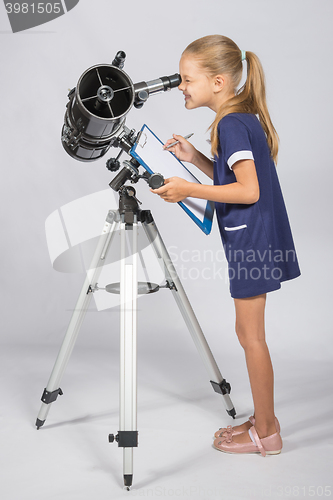 Image of The young astronomer happy to look through the telescope recording observations