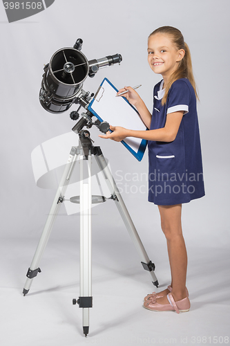 Image of Happy girl astronomer looks happy in the picture standing next to the telescope