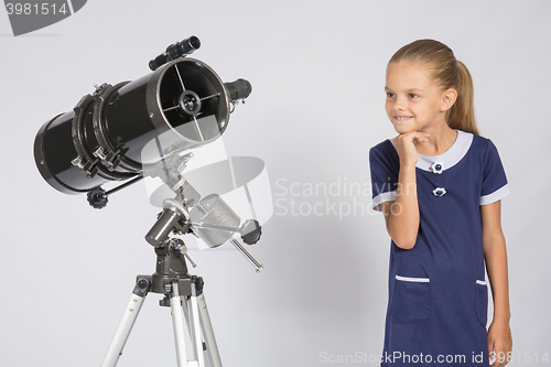 Image of Seven-year girl with interest looking at a reflector telescope