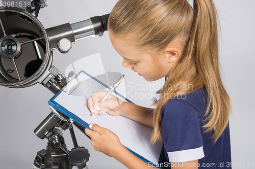 Image of Girl astronomer writes on a sheet of paper of a starry sky with your telescope