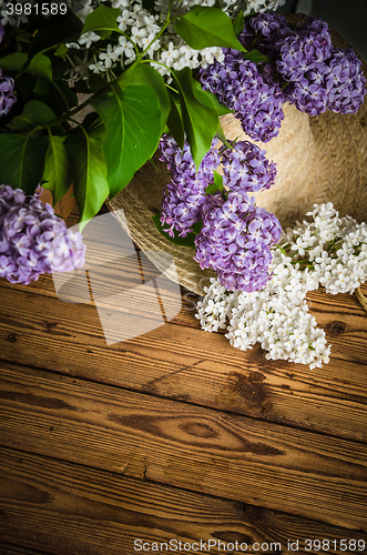 Image of Bouquet of lilacs and a straw hat, close-up