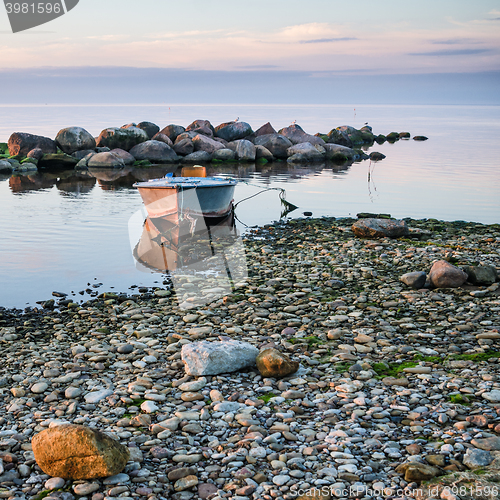 Image of Rocky shore of the sea and fishing boat at sunset