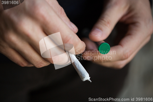 Image of close up of addict hands with marijuana joint tube